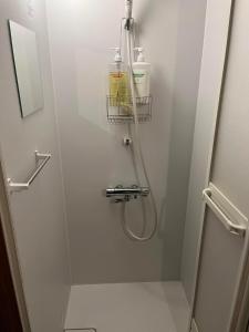 a bathroom with a shower stall with a hose at Guesthouse Kazura in Nanto