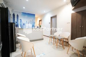 a meeting room with white chairs and a painting on the wall at Eascot Hotel Mitra RedDoorz in Jakarta