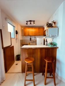 a kitchen with a counter and two stools in it at Pé na areia! Apart hotel com vista para o mar e lazer completo! Front beach apartment with ocean view and amenities! in Rio de Janeiro