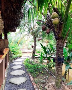 a garden with two palm trees and a walkway at Phuc Sinh Homestay in Ben Tre
