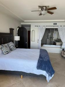 a bedroom with a large bed with a ceiling fan at Playa Bonita Rosarito in Rosarito