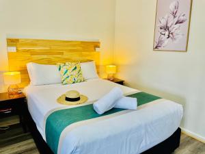 1 dormitorio con 1 cama con sombrero en Highway Motor Inn Taree, en Taree
