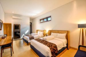 a hotel room with two beds and a desk at Rumah Mertua Heritage in Yogyakarta