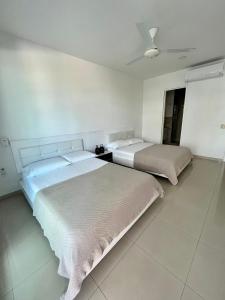 two beds in a room with white walls at Morros Ultra 810 in Cartagena de Indias