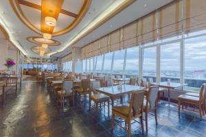 un restaurante con mesas, sillas y ventanas grandes en Asia Airport Hotel, en Bangkok