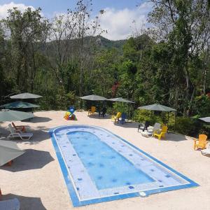 einen Pool mit Stühlen, Tischen und Sonnenschirmen in der Unterkunft Finca Pozo Azul in La Vega