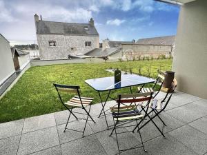 einen Tisch und Stühle auf einer Terrasse mit Rasen in der Unterkunft Appartement Étel, 3 pièces, 4 personnes - FR-1-479-144 in Étel