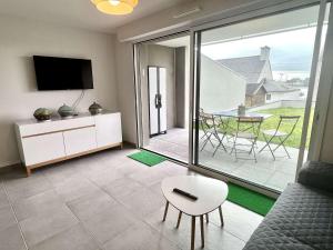 ein Wohnzimmer mit einem TV, einem Sofa und einem Tisch in der Unterkunft Appartement Étel, 3 pièces, 4 personnes - FR-1-479-144 in Étel