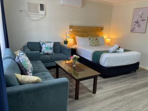 a hotel room with a bed and a couch and a table at Highway Motor Inn Taree in Taree