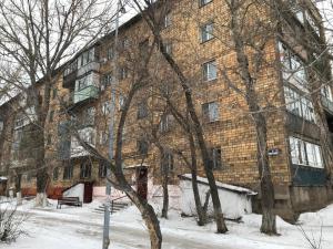a large brick building with trees in the snow at Apartments in the city center in Karagandy