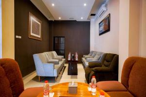 a waiting room with couches and chairs and a table at RedDoorz Premium at Raja Hostel Syariah in Hajimana