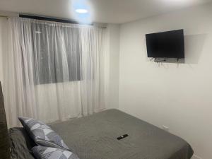 1 dormitorio con 1 cama y TV de pantalla plana en Apartaestudio de lujo con excelente vista!!, en Ibagué