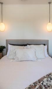 Una cama con sábanas blancas y almohadas. en Petit Manor, en Cromer