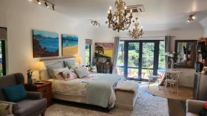 a bedroom with a bed and a chair and a chandelier at Boutique Art Retreat in Upper Hutt