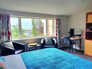 una camera con letto, sedie e finestra di Extended Stay City Hostel a Dunedin