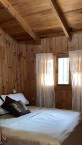 a bedroom with a bed with wooden walls and a window at Cómoda Cabaña El puchero ,Surutato, el Puchero in Surutato