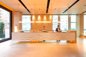 Due persone sedute alla scrivania in un ufficio di AKI Hong Kong - MGallery a Hong Kong