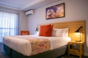 a hotel room with a large bed with orange pillows at Potters Toowoomba Hotel in Toowoomba