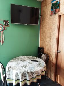 Habitación con mesa y TV en una pared verde. en Apartamento a dos cuadras de Plaza de Toros y Rambla, en Colonia del Sacramento