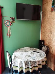 una mesa y sillas con TV en una pared verde en Apartamento a dos cuadras de Plaza de Toros y Rambla, en Colonia del Sacramento