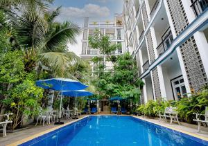 贡布Kampot View Boutique的建筑物旁边有带椅子和遮阳伞的游泳池