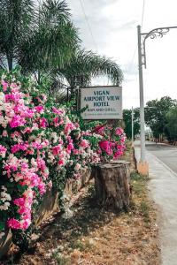 un cartel para un nuevo motel con vistas al aeropuerto y flores rosas en Airport View Hotel Vigan en Vigan