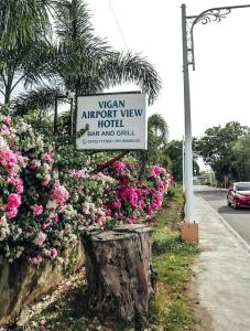 a sign for a virgin airport view hotel next to pink flowers at Airport View Hotel Vigan in Vigan