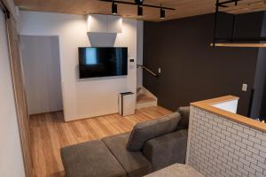 a living room with a couch and a tv on a wall at Second Home 瀬戸風月 in Takamatsu