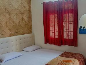 a bedroom with a bed and a window with red curtains at Adrose Cotttages & Family Restaurant Colva in Colva