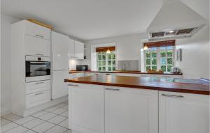 cocina con armarios blancos y encimera de madera en 6 Bedroom Awesome Home In Kvrndrup, en Kværndrup