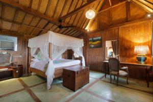 - une chambre avec un lit à baldaquin et un bureau dans l'établissement Villa O'Hea Ubud, à Ubud