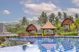 een zwembad van het resort met twee hutten op de achtergrond bij The Kleep Jungle Resort in Nusa Penida