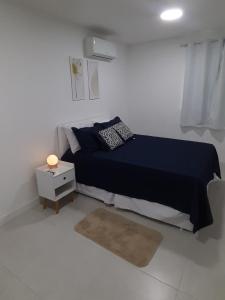 1 dormitorio con cama azul y mesita de noche en Golden Lake - Arraial do Cabo, en Arraial do Cabo