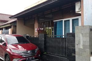 un coche rojo estacionado frente a una casa en Cheerfull residential home - Dillair Home Stay, en Talang Kelapa
