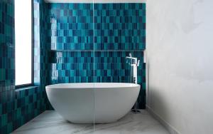 a bath tub in a bathroom with green tiles at Mercure Bukhara Old Town in Bukhara