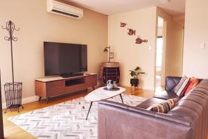 uma sala de estar com um sofá e uma televisão de ecrã plano em Rooftops On Henrycentre Of West End Cafes em Fremantle