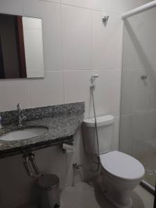 a bathroom with a toilet and a sink and a mirror at Apartamento em Cabo Frio RJ - Praia das Dunas in Cabo Frio