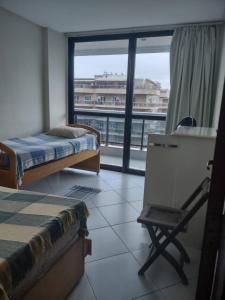 a room with two beds and a desk and a window at Apartamento em Cabo Frio RJ - Praia das Dunas in Cabo Frio