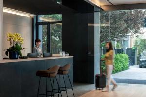 a woman walking past a bar in a building at base-Beijing Sanlitun Serviced Apartment in Beijing