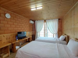a bedroom with two beds and a tv in a room at Jeju Hanibaram Pension in Jeju