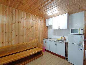 a kitchen with a bench and a white refrigerator at Jeju Hanibaram Pension in Jeju