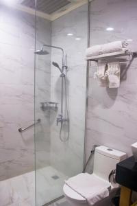 uma casa de banho com uma cabina de duche em vidro e um WC. em Le Charmé Suites - Subic em Olongapo