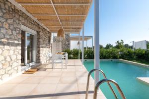patio ze stołem i krzesłami przy basenie w obiekcie New Loft by Ossiano Pool Villas, Heating Pool,2 min drive to Haraki Beach & 10 to Lindos w mieście Charaki +15 zdjęć