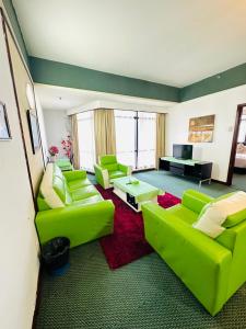 een woonkamer met groene banken en een piano bij KL Cozy Suite Times Square in Kuala Lumpur