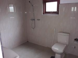 a bathroom with a shower and a toilet and a window at C-Lanka Guest House in Aluthgama