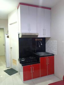 uma cozinha com armários vermelhos e brancos e um lavatório em Comfort 2BR green pramuka bougenvile em Jakarta