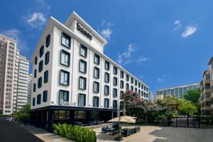 a large white building with benches in a city at base-Beijing Sanlitun Serviced Apartment in Beijing