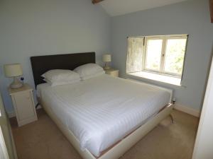 a white bed in a room with a window at Clifton Cottage at Lovelady Shield in Alston