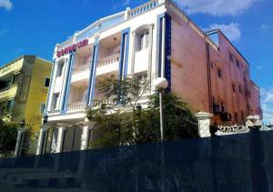 um edifício com janelas azuis e uma cerca em frente em Bonne Vie Hotel em Cidade 6 de Outubro