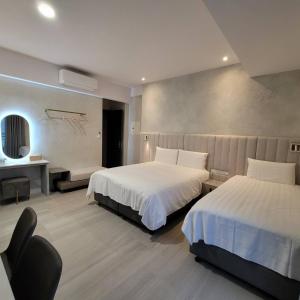 a hotel room with two beds and a desk at 芙蘿拉萃旅 in Taitung City